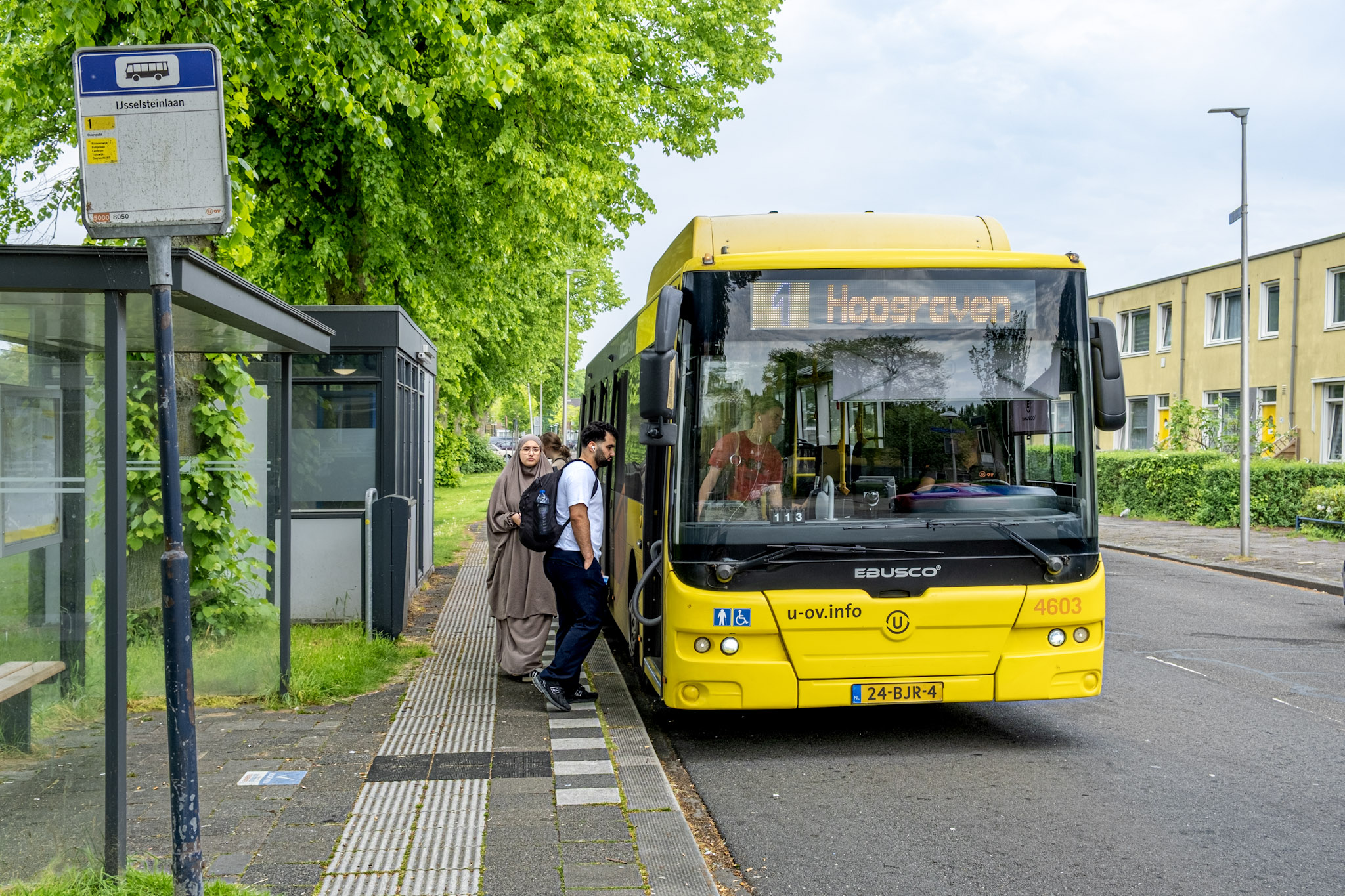 Bus bij bushalte met instappende passagiers